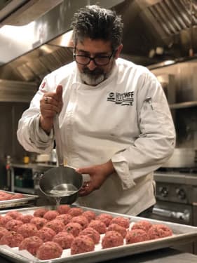 Master Chef Marco Barrila rolling meatballs in a professional kitchen.